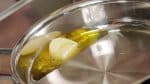 Préparons la paella. Versez l'huile d'olive dans une poêle et ajoutez-y l'ail haché. Chauffez à feu doux. N'hésitez pas à inclinez la poêle pour recouvrir complètement l'ail d'huile.