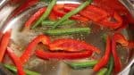 Ensuite, ajoutez des lanières de poivron rouge de 1cm (0,4") et les haricots verts coupés en deux. Salez et poivrez. Faites revenir les légumes à la poêle.