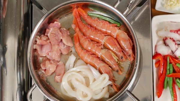 Add the prawns, squid rings and chicken pieces. Season the chicken with salt. Then, sprinkle pepper on all the ingredients. If there isn’t enough oil, add more.