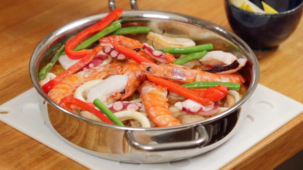 Remove the pan from the oven and place it onto a trivet. Arrange the octopus. And distribute the red bell pepper and string bean pods.