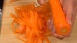 Sau đó, cạo ra các dải cà rốt dài và mỏng bằng dao gọt vỏ.