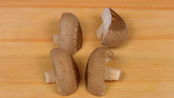 Retirez le bout terreux des champignons shiitake, faites une entaille dans les chapeaux et séparez-les en deux.