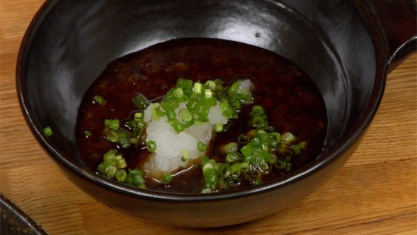 Meanwhile, pour the homemade ponzu sauce into a bowl and add the grated daikon radish and chopped spring onion leaves.