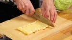 Let's prepare the aburaage, thin deep-fried tofu. Remove the excess oil with a paper towel. Lightly warming the aburaage in a microwave beforehand will help remove the oil. Cut the aburaage into bite-size pieces.