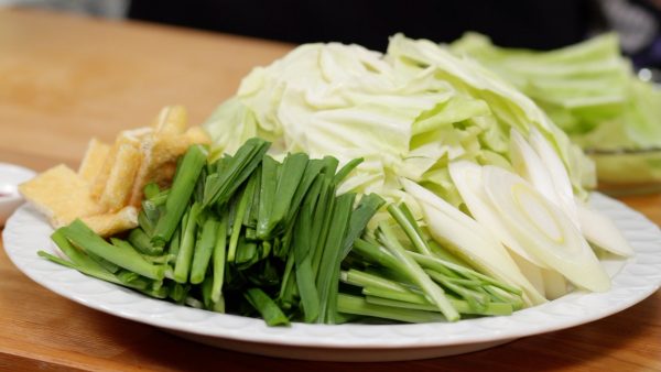 将韭菜切成5厘米（2英寸）的小块，将叶和茎分开，将大葱斜切成1厘米（0.4英寸）的薄片。
