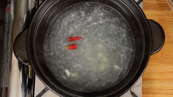 それでは土鍋を使ってちゃんこ鍋を作ります。チキンスープ、酒、塩、砂糖、おろしにんにくを入れて軽く混ぜます。赤唐辛子を加えて中火で熱します。