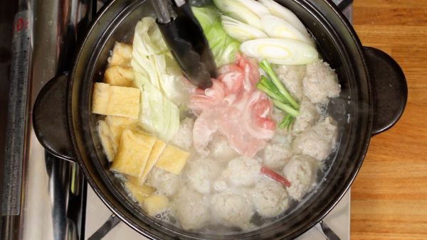 Ajoutez l'aburaage, le tofu fin frit, les feuilles chou, le poireau en tranches diagonales, la partie tige de la ciboule chinoise, et les tranches de porc super fines. Nous allons utiliser des tranches de porc pour le shabu-shabu, une fondue japonaise.