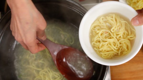 当面条热起来时，将它们放入碗中。 把汤舀在拉面上。