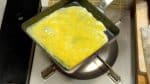 在煎鍋內倒油加熱，檢查表面油溫是否夠高。倒入三分之一蛋液，並迅速將其在鍋內攤開。