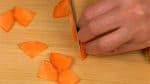 现在我们来切配料。将胡萝卜竖切四份，然后再切成1/4的圆形切片。