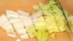 将白菜的根茎切掉，再把菜叶切成3到4厘米的小段。把白菜叶白色坚实的部分和绿叶的部分分开。
