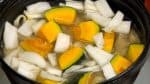 Den Kabocha Kürbis sowie den festen weißen Teil des Chinakohls in den Topf geben. Das Gemüse mit einer Kelle in die Brühe untertauchen. Auf mittlere niedrige Hitze aufdrehen, zudecken und erneut zum Kochen bringen.