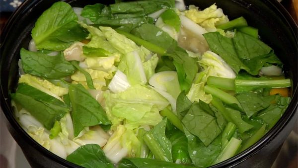 Now, drop in the long green onion, leafy part of the hakusai and komatsuna spinach. Simmer for about 2 more minutes.