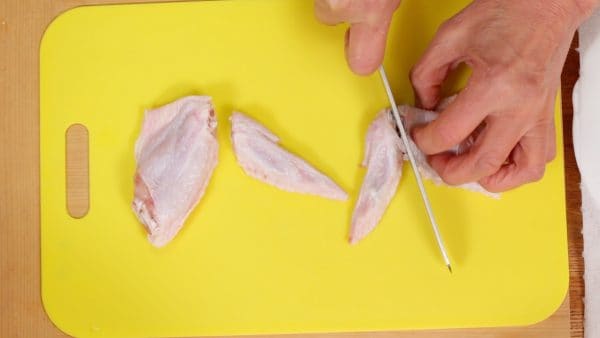 First, let’s prepare the chicken wings. Insert the blade of a knife into the joints and detach the wing tips. Originally, the broth of Kiritanpo Nabe is made from the bones of local Hinai chicken but we’re substituting with easily available chicken wings.