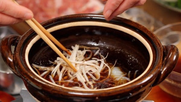 Add the lightly parboiled shirataki noodles first since they will take more time to absorb the broth. Add the burdock root, which also takes time to soften.