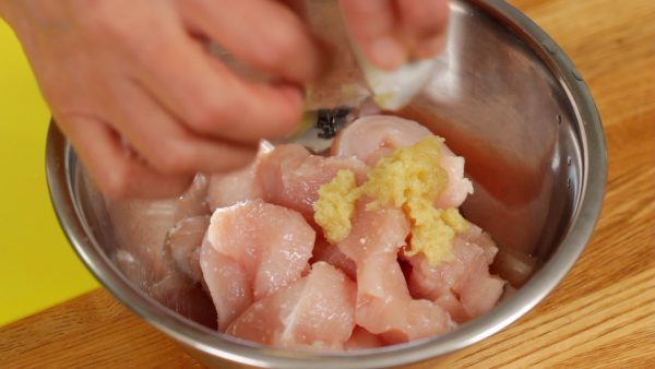 Next, place the chicken pieces into a bowl. Add the salt, sugar, sake, grated garlic and ginger root.