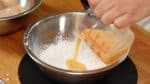 Ensuite, ajoutez l'eau froide aux œufs battus et mélangez. Ajoutez les œufs dilués au mélange de farine. 
