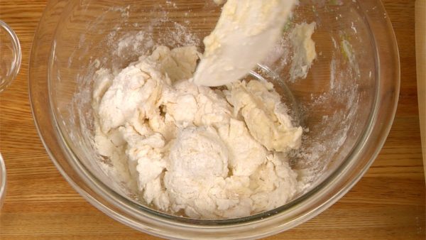 搅拌直到面粉均匀地吸收水分并且完全润湿。 将面团刀片放入食品加工机中，用刮刀刮去抹刀上其余的面团。