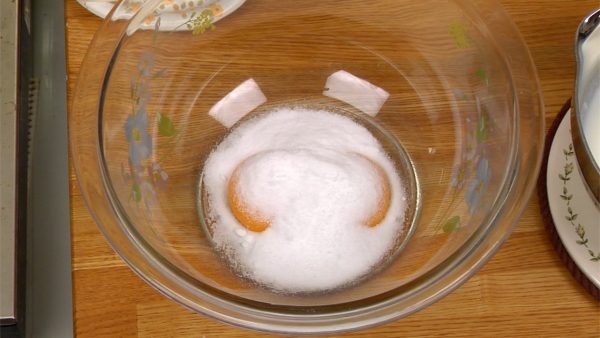 Vamos fazer o creme de chocolate. Adicione o açúcar às duas gemas de ovo em uma vasilha e mexa bem com um fuê.