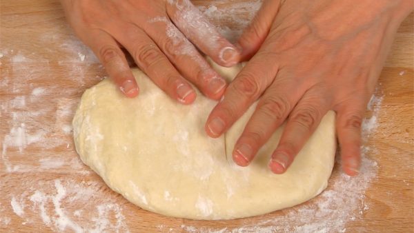 Để bột nhồi lên khay bánh ngọt được phủ bột bánh mì. Làm phẳng bột nhồi bằng tay bạn và loại bỏ khí bên trong.