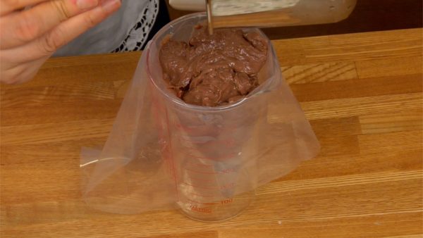 Let’s make the chocolate cornets. Remove the plastic wrap from the chilled chocolate custard. Lightly mix it to soften. Put the custard in a pastry bag.