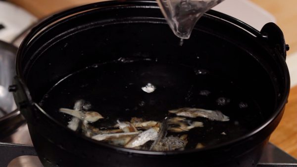 Pour the water into a pot along with the niboshi, dried baby sardines. And turn on the burner.