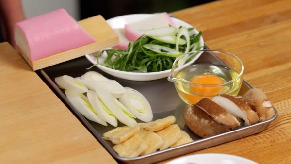 Cut the aburaage, thin deep-fried tofu into bite-size pieces, and cut out 6 slices of the long green onion. As for the spring onion leaves, slice them thinly.