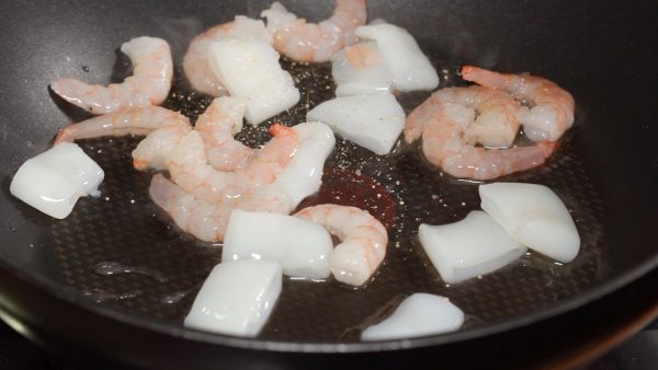 Place the seafood into the heated pan and distribute evenly. Add the white wine and the white pepper. Cover and lightly simmer the seafood.