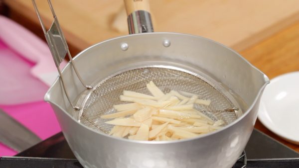 Now, lightly boil the bamboo shoot in a pot of boiling water. This will help to remove the excess water and absorb the sauce later. Remove and strain it with a mesh strainer.