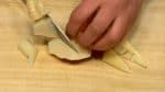 Coupez l'extrémité des pousses de bambou cuites, et ensuite coupez-les en deux dans la longueur. Coupez le reste des pousses de bambou en quartiers en les tournant. 