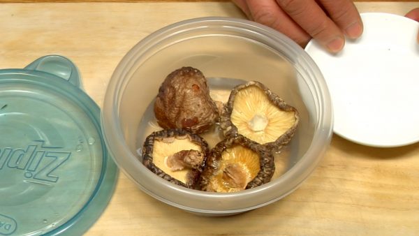 Put the pre-washed dried shiitake mushrooms in a container. Add water.