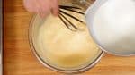 牛乳を少しずつボウルに加えよく混ぜます。半分くらいまで加えたら鍋をコンロに置きます。卵液をしっかり混ぜます。