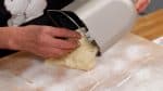 Rắc một lớp mỏng bột bánh mì lên khay nặn, và bỏ chảo làm bánh ra khỏi máy làm bánh mì. Phủ tay bạn bằng bột, và để bột nhồi lên khay. Rắc nhẹ bột lên bột nhồi lần nữa.