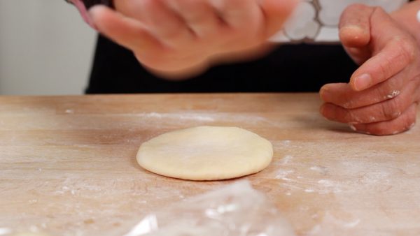 Place one dough piece onto the kneading board, thinly dust the surface with flour, and slap or flatten the dough to remove the gas inside.