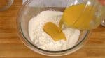 Avec une spatule, faites un puits au centre de la farine. Versez le mélange d’œuf dans le trou. 