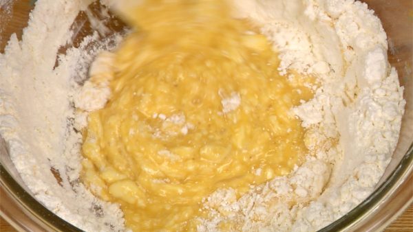 Gradually break the edges of the hole and mix in the flour from the center to the outside. This will help avoid pockets of flour.