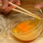 把兩粒蛋打入碗裡。用筷子把蛋白搓搓，再用筷子輕輕的把蛋黃與蛋白打一下，不需打的太均勻。如果蛋打的太用力，親子丼會失去嫩滑的口感。