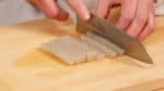 Schneide den Konjak-Shirataki-Block in etwa 1 cm große Stücke. Alle Zutaten in die gleiche Größe wie die Sojabohnen zu schneiden lässt das Gericht schöner und harmonischer erscheinen und sorgt für eine ausgewogene Balance der Zutaten. 