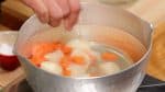First, place the potato pieces and the sliced carrot into a pot of a large amount of water. Add the salt.