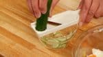 Now, slice the cucumber with a slicer. Add the salt and distribute evenly.