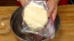 Mettez la pâte dans un sac plastique alimentaire, et repliez-le au milieu. La pâte n'est pas lisse à ce stade, et va facilement s'émietter. 