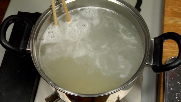 Rüht die Nudeln mit Kochstäbchen leicht um, damit sie nicht am Boden festkleben. Wenn das Wasser wiederum aufkocht, dreht den Herd zurück. 