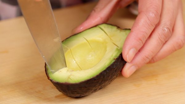 Cut the avocado in half lengthwise and make 4 cuts in the flesh. Then, slice across the initial cuts.
