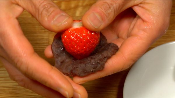 Hold the tip of a strawberry in the center and spread the anko up to the stem.