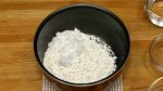 Ajoutez la farine de riz gluant (mochiko ou shiratamako) dans un bol anti-adhésif avec le sucre. Mélangez. 