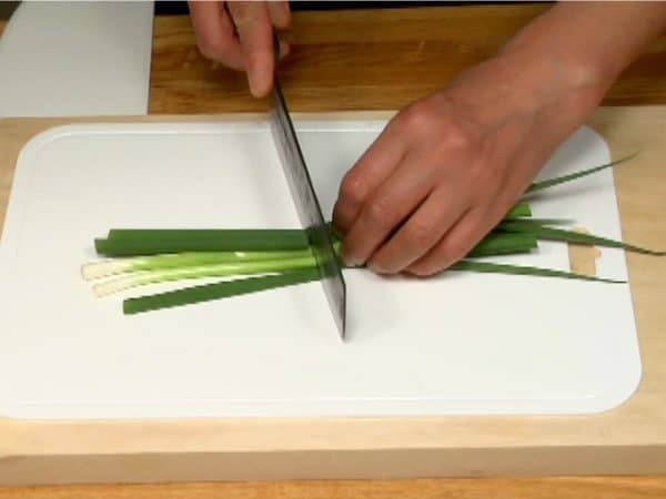 Quarter the spring onion leaves, stack and chop them into fine pieces.