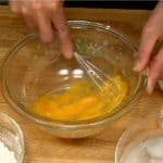 Préparons la pâte à takoyaki. Casser un oeuf dans un bol et le battre avec un fouet.