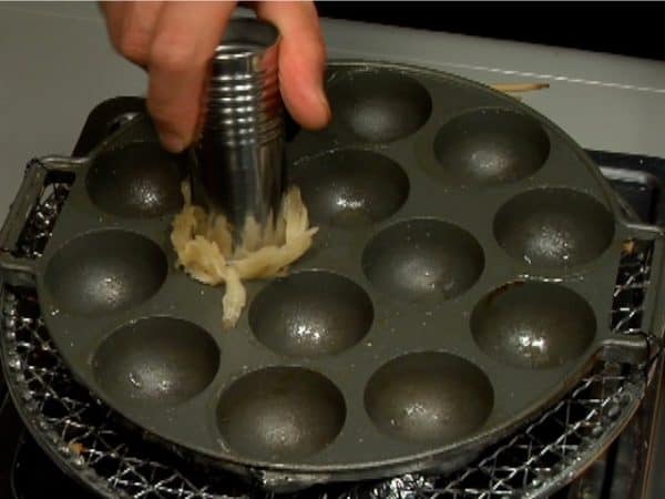 Let's make Takoyaki. Turn on the burner and grease the whole surface of the takoyaki pan.