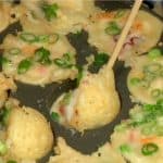Incliner les takoyaki à 90 degrés, faisant couler la pâte encore crue dans les trous.