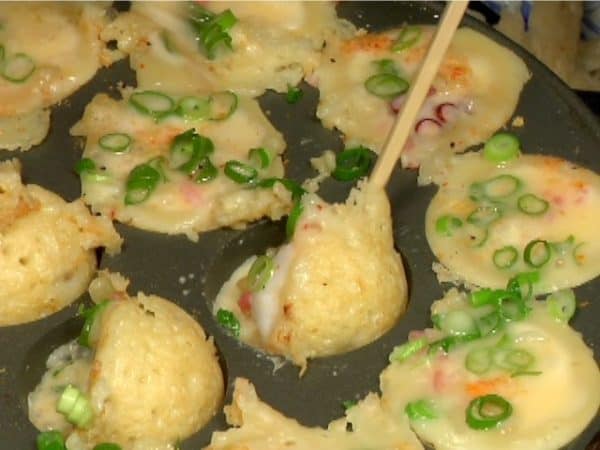 Incliner les takoyaki à 90 degrés, faisant couler la pâte encore crue dans les trous.